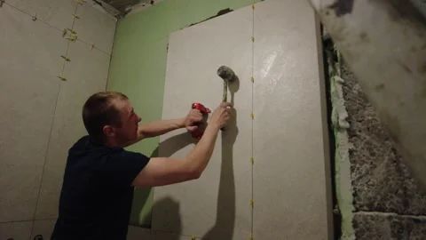Installing wall tiles in a bathroom renovation project during evening hours Stock-Footage 332477406