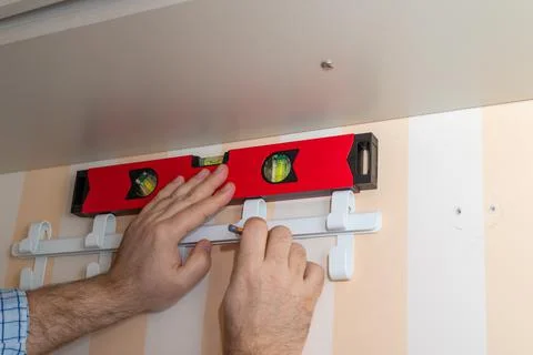 Installing wardrobe hooks with a bubble level tool Stock Photos