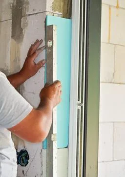 Installing white polystyrene foam board insulation on a bare wall next to window Stock Photos