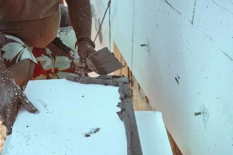 Installing white polystyrene heat insulation, detail on worker hand putting.. Stock Photos