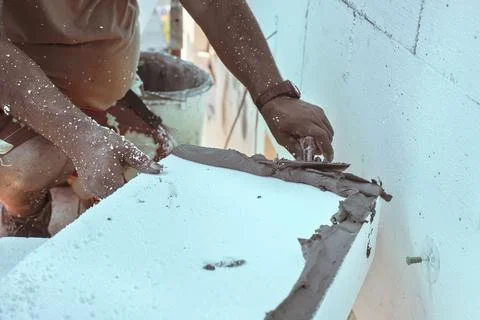 Installing white polystyrene heat insulation, detail on worker hand putting.. Stock Photos