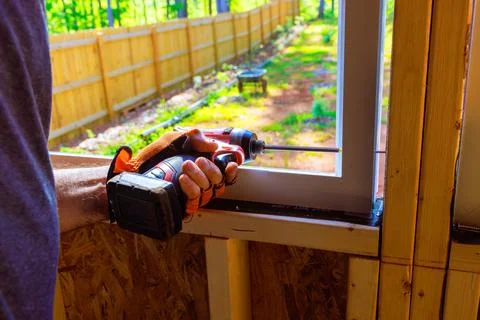 Installing window in new house requires use of screwdriver by a construction Stock Photos