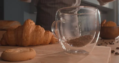 Instant coffee granules are poured into a transparent cup Stock Footage 243499607