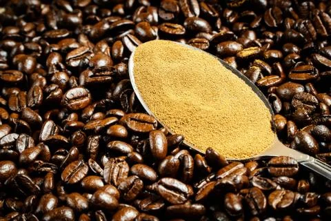 Instant coffee in spoon on coffee beans background Stock Photos