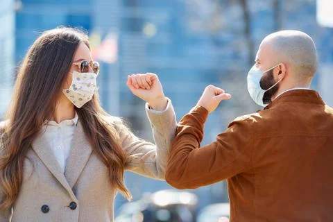 Instead of greeting with hug or handshake man and woman bump elbows on a stre Stock Photos