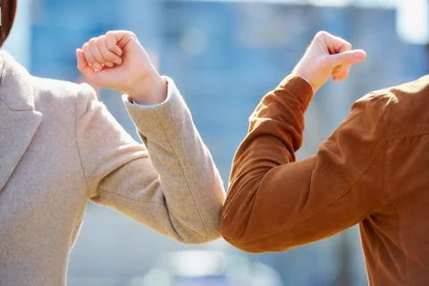 Instead of greeting with hug or handshake man and woman bump elbows on a stre Stock Photos