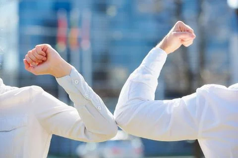 Instead of greeting with hug or handshake man and woman bump elbows on a stre Stock Photos