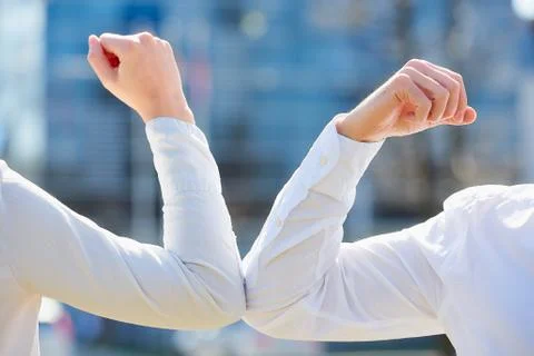 Instead of greeting with hug or handshake man and woman bump elbows on a stre Stock Photos