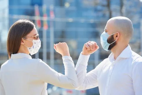Instead of greeting with hug or handshake man and woman bump elbows on a stre Stock Photos