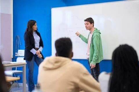 Institute students solving math equation on whiteboard with teacher Stock Photos