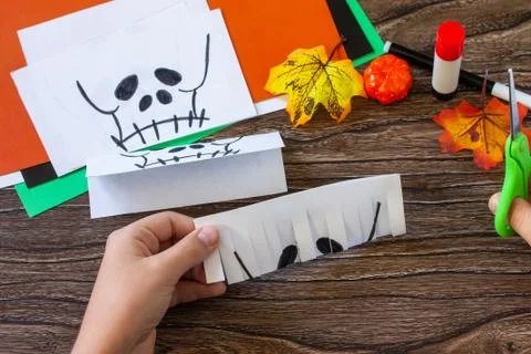 Instruction step 5. Child creates Halloween decor, paper lanterns garland sku Foto stock