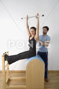 Instructor adjusting posture of woman exercising on pommel horse Stock Photos