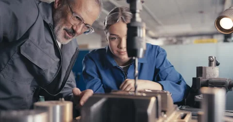 Instructor and apprentice watching metal drill in workshop Video stock 254676972
