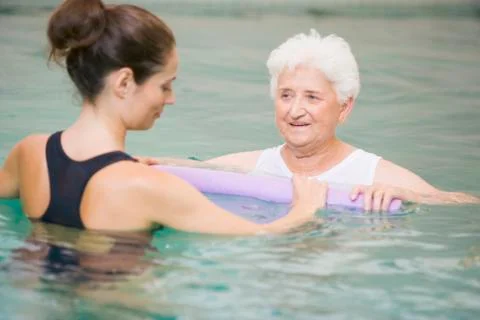 Instructor And Elderly Patient Undergoing Water Therapy Stock Photos