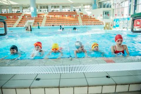 Instructor and group of children doing exercises near a swimming pool Stock Photos
