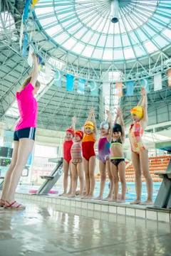 Instructor and group of children doing exercises near a swimming pool Stock Photos