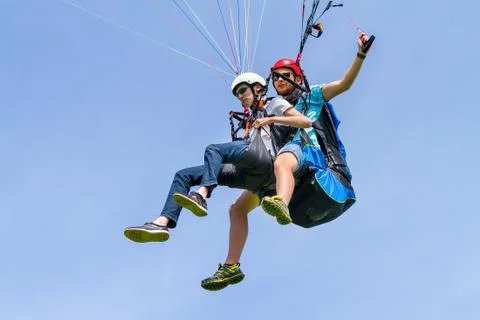 Instructor and paraglider flying in sky Stock Photos
