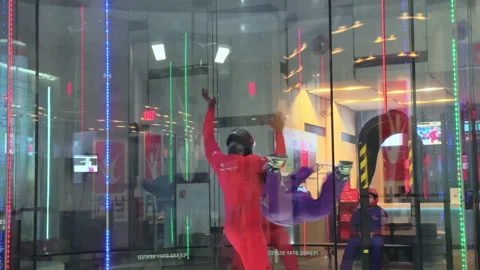 Instructor and student floating horizontally inside skydiving wind tunnel Stock Footage 320147050