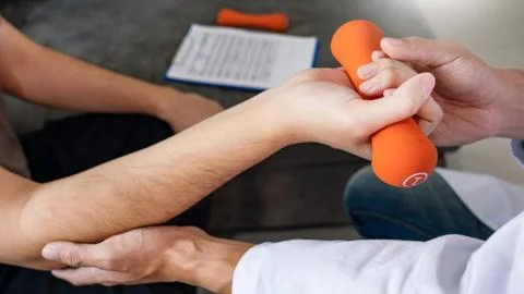 Instructor assisting senior doing exercise working out in clinic strengthenin Stock Photos