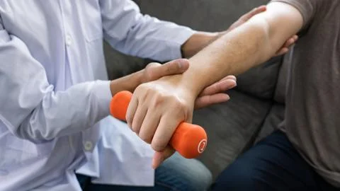 Instructor assisting senior doing exercise working out in clinic strengthenin Stock Photos