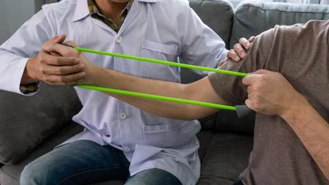 Instructor assisting senior doing exercise working out in clinic strengthenin Stock Photos