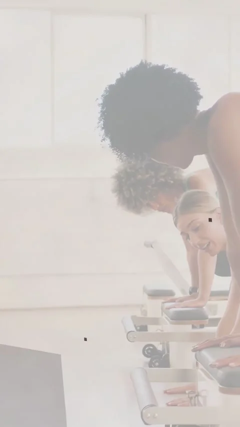 Instructor cueing alignment while three women holding plank on Pilates reformers Stock Footage 332507189
