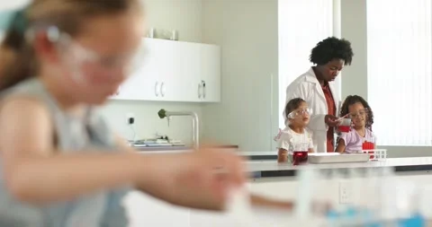 Instructor demonstrating red beaker child handling pipette and test tubes at lab Stock Footage 339320843