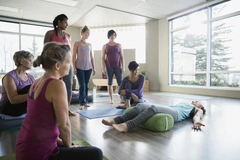Instructor demonstrating supported corpse pose in restorative yoga Stock Photos