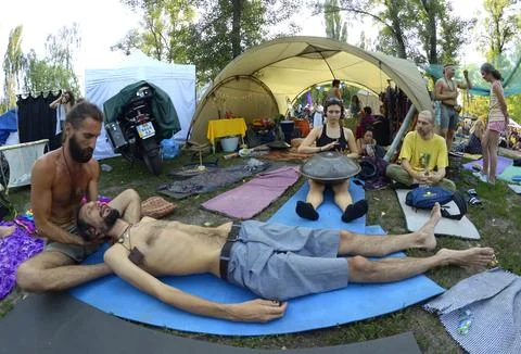 Instructor doing massage to the man lying on karemat, people relaxing aroun.. Stock Photos