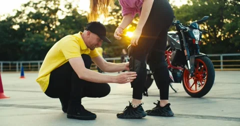 Instructor in a driving school in a yellow t-shirt helps a girl put on Stock Footage 249843921