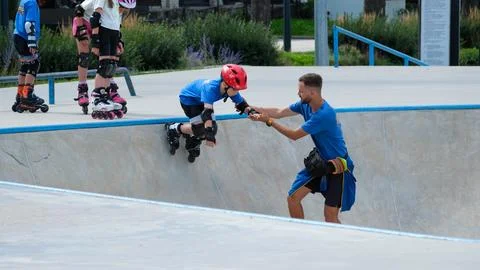 Instructor Helping Child Learn Inline Skating at Skatepark Stock Photos