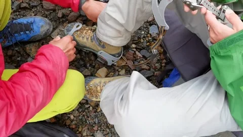 The instructor helps the tourist to try on the crampons. Shot close-up. Stock Footage 173746713