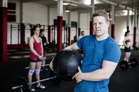 Instructor Holding Medicine Ball While Woman Exercising With Bar Stock Photos
