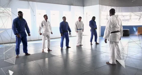 Instructor leading students adjusting belts mirroring arm circles in martial Stock Footage 327942899