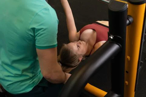 Instructor led training helps a beautiful client to perform exercises in a Stock Photos