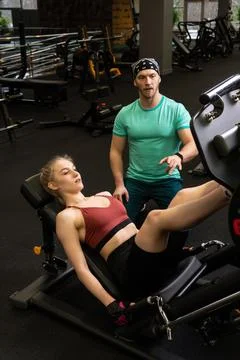 Instructor led training helps a beautiful client to perform exercises in a Stock Photos