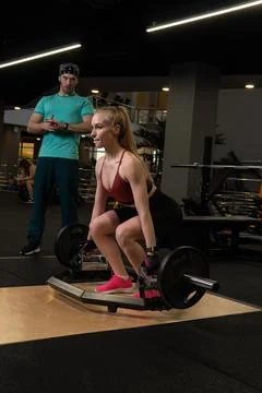 Instructor led training helps a beautiful client to perform exercises in a Foto stock