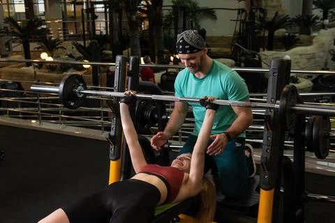 Instructor led training helps a beautiful client to perform exercises in a Stock Photos