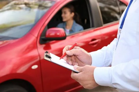 Instructor near woman in car, outdoors. Passing driving license exam Stock Photos