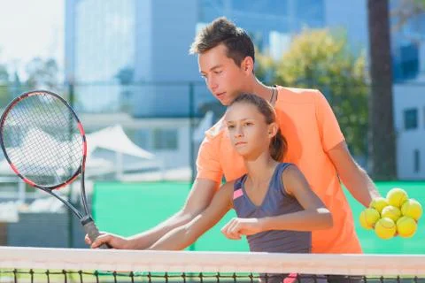 Instructor or coach teaching child how to play tennis on a court indoor Stock Photos