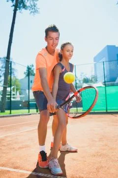 Instructor or coach teaching child how to play tennis on a court indoor Foto stock