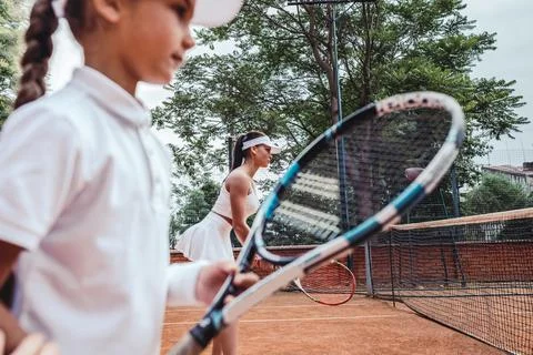 Instructor or coach teaching child how to play tennis on a court Stock Photos