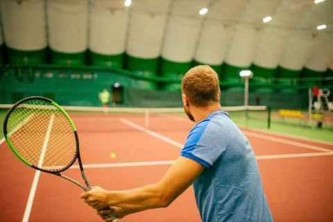 Instructor or coach teaching how to play tennis on a court indoor Stock Photos
