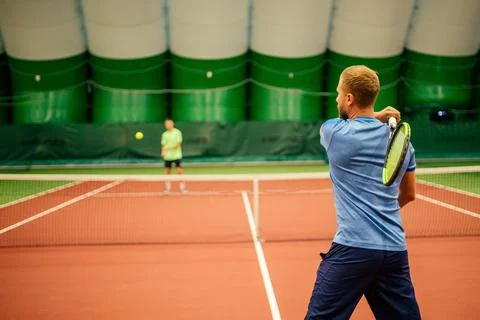 Instructor or coach teaching how to play tennis on a court indoor Stock Photos