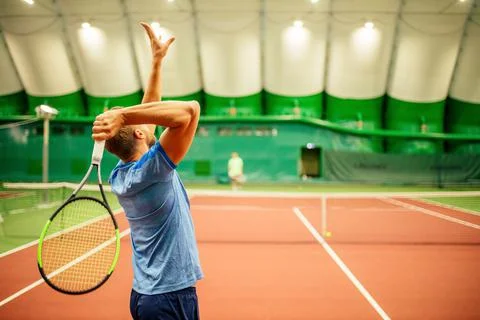 Instructor or coach teaching how to play tennis on a court indoor Stock Photos