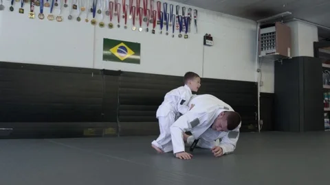 Instructor practicing Jiu-jitsu moves with a boy 動画素材 77080529