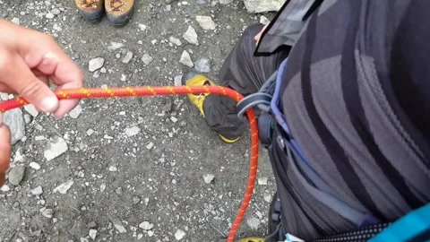 Instructor prepares knots on climbing equipment before climbing Stock Footage 173746844