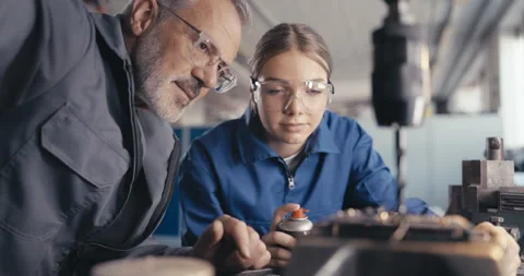 Instructor showing apprentice to cool metal drill in workshop Stock Footage 254676237