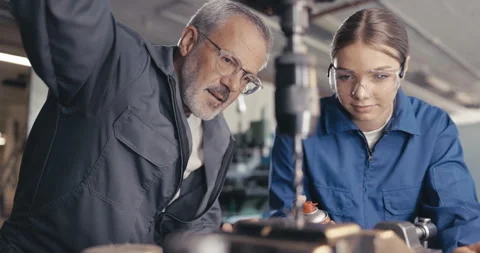 Instructor showing apprentice to cool metal drill in workshop Video stock 254676557