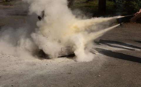 Instructor showing how to use a  fire extinguisher on a training fire. Stock Photos